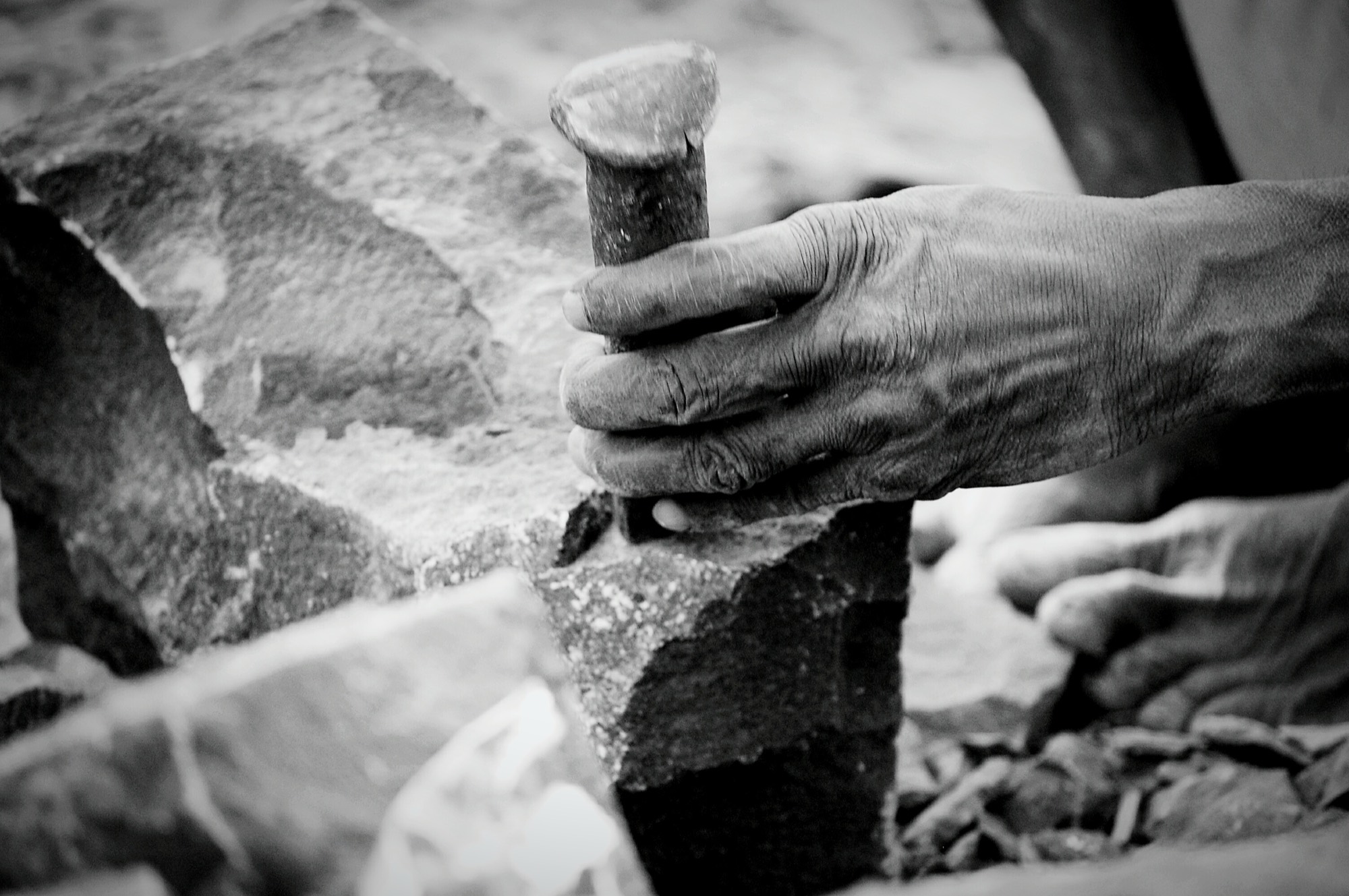 A stonemason's hand chiselling sandstone